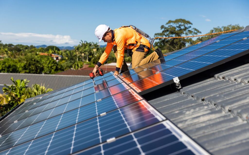 Investir em Energia Solar ou Deixar o Dinheiro no Banco? Entenda o Que Vale Mais a Pena Instalacao profissional como investir em energia solar com seguranca Técnico especializado instala sistema de energia solar em telhado residencial, etapa essencial para quem decide investir em energia solar.